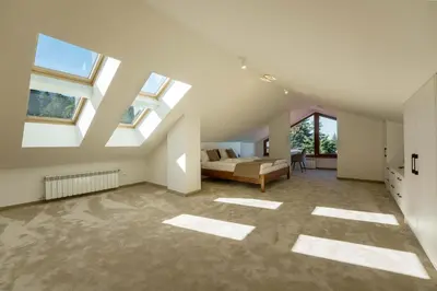 a large attic room with a bed and windows at Musala Hotel in Borovets