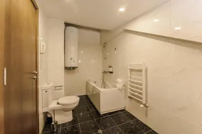 a white bathroom with a toilet and a sink at Musala Hotel in Borovets