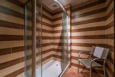 a bathroom with a shower and a chair next to a tub at Hotel Ego - Free Parking - Top Central Location in Plovdiv