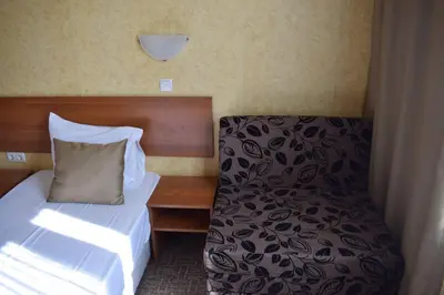 a small bedroom with a bed and a chair at Slavyanska Beseda Hotel in Sofia