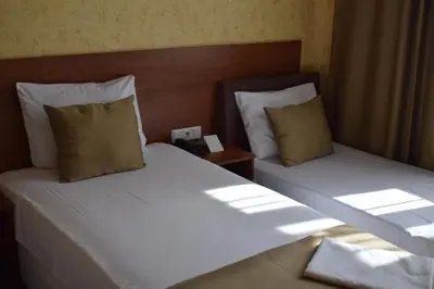 two twin beds in a hotel room with sunlight shining on them at Slavyanska Beseda Hotel in Sofia