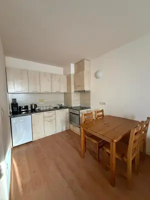 a kitchen with a wooden table and wooden chairs at PM Services Royal Plaza Apartments in Borovets