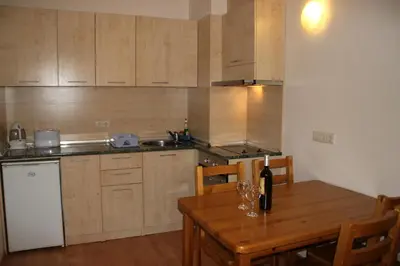 a kitchen with a wooden table with a bottle of wine at PM Services Royal Plaza Apartments in Borovets
