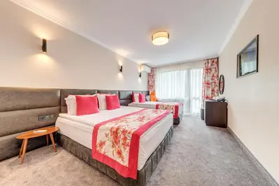 a hotel room with two beds and a couch at SPA Hotel Kiparis in Smolyan