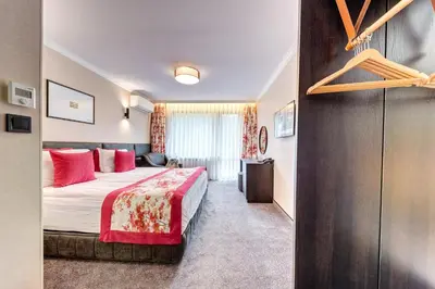 a hotel room with a bed with red pillows at SPA Hotel Kiparis in Smolyan