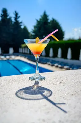 a drink sitting on a table next to a pool at Hotel Montecito in Sofia