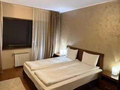 a bedroom with a bed with white sheets and a window at Hotel Smilen in Smolyan