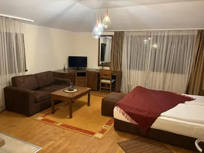 a bedroom with a bed and a couch and a table at Hotel Smilen in Smolyan