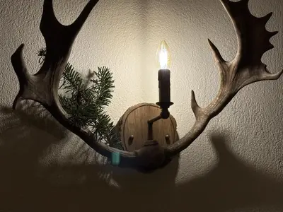 a candle on a holder with antlers on a wall at Hotel Smilen in Smolyan