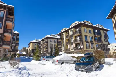 a snow covered parking lot in front of buildings at Hotel Bojur & Bojurland Apartment Complex in Bansko