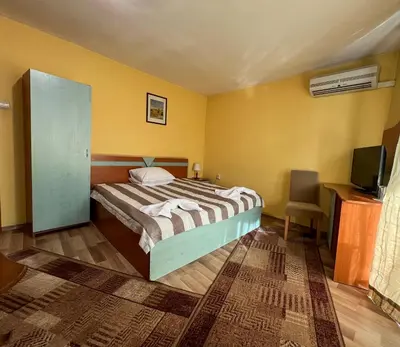a bedroom with a bed with yellow walls and a television at ALPHA family HOTEL in Blagoevgrad