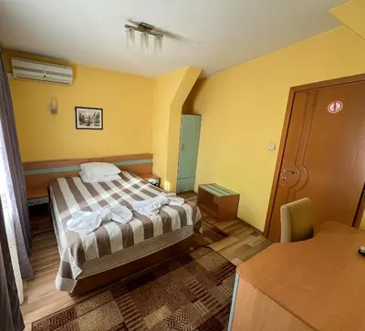 a bedroom with a bed in a room with yellow walls at ALPHA family HOTEL in Blagoevgrad