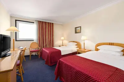 a hotel room with two beds and a flat screen tv at Ramada by Wyndham Sofia City Center in Sofia