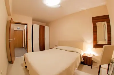 a bedroom with a white bed and a chair at Green Life Family Apartments Pamporovo in Pamporovo