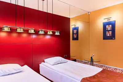 two beds in a room with a red wall at Monet Hotel in Plovdiv