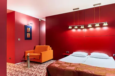 a red bedroom with a bed and a chair at Monet Hotel in Plovdiv