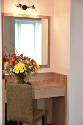 a table with a vase of flowers and a mirror at Budapest Hotel - Free Parking in Sofia
