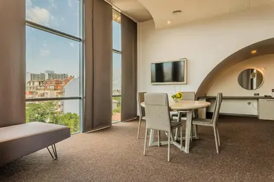 a room with a table and chairs and a tv at Budapest Hotel - Free Parking in Sofia