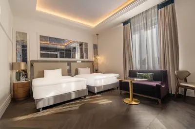 a hotel room with two beds and a chair at Sofia Balkan Palace in Sofia