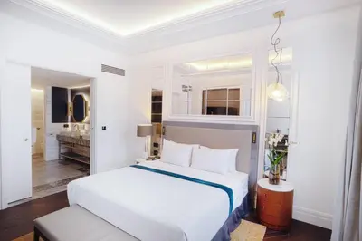 a white bedroom with a bed and a bathroom at Sofia Balkan Palace in Sofia