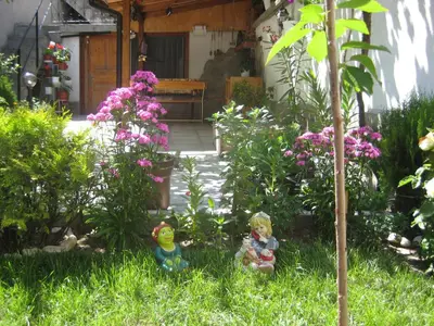 a garden with two figurines in the grass with flowers at Aseva House Guest house in Bansko
