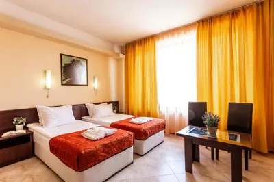 a hotel room with two beds and a table at Spa Hotel Aspa Vila in Banya