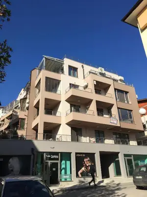 a man walking in front of a tall building at Apartment Park Sveti Vrach in Sandanski