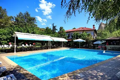 a large blue swimming pool with tables and chairs at Хотел Свети Трифон in Melnik