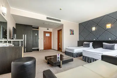 a hotel room with two beds and a couch at Hotel Noris in Plovdiv