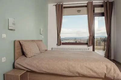 a bedroom with a bed with a large window at Vila Lidia in Tsigov Chark