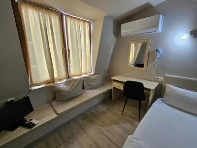 a small room with a bed and a desk and a window at Hotel Racic Self-Check In in Voyvodinovo