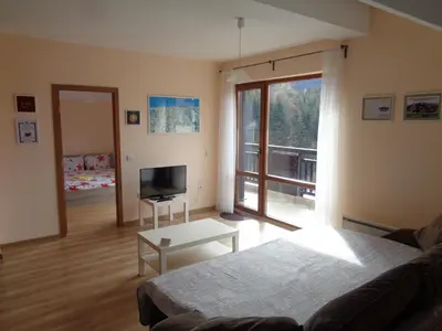 a living room with a couch and a large window at Yastrebetz view in Borovets
