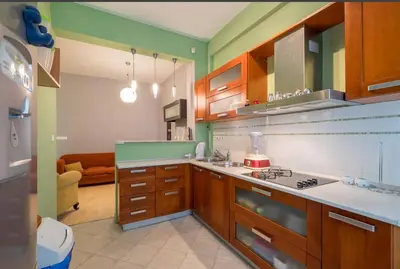 a kitchen with wooden cabinets and green walls at Han Krum 2 Bedroom Central Flat in Sofia