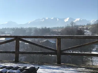 a wooden fence with snowy mountains in the background at Das Landhaus in Bachevo