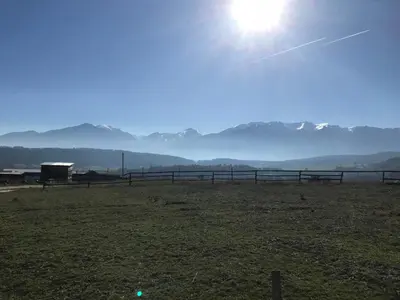 a field with a fence and mountains in the background at Das Landhaus in Bachevo