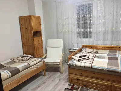 a bedroom with two beds and a chair and a window at Elenite Guesthouse in Gotse Delchev