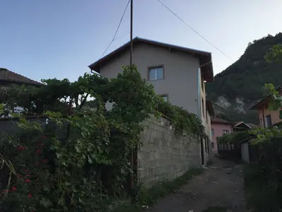 a small white house with a brick wall at Elenite Guesthouse in Gotse Delchev