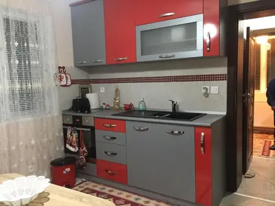 a kitchen with red cabinets and a sink at Elenite Guesthouse in Gotse Delchev