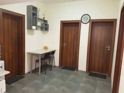 a room with two doors and a table and a clock at Rooftop Oscar Rooms in Sofia