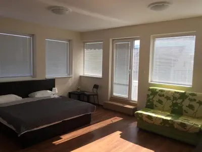 a bedroom with a bed and a couch and windows at Rooftop Oscar Rooms in Sofia
