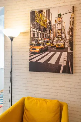 a yellow couch against a brick wall with a picture of a street at 5th Avenue Sofia Two Bedroom, Two Bathroom, Positano Street Suite by Flat Mаnager in Sofia