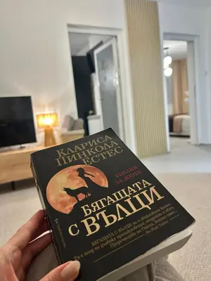 a person holding a book in a living room at Guest House Rila in Govedartsi