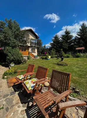 a group of three wooden chairs sitting in a yard at Guest House Rila in Govedartsi