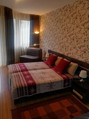 a bedroom with a bed with red pillows and a chair at Snowdrop Studio in Borovets