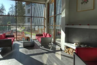a living room with red chairs and a fireplace at Euphoria Club Hotel in Borovets