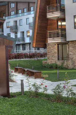 a park with benches and tables in front of buildings at Euphoria Club Hotel in Borovets