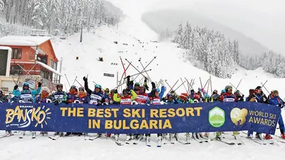 a group of skiers standing behind a sign in the snow at PIRIN PLACE Bansko in Bansko