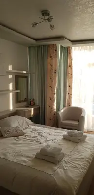 a bedroom with a white bed with a chair and a window at Luxury Two Bedroom Flat in Blagoevgrad