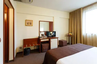 a hotel room with a bed and a desk and a mirror at Nadejda Hotel in Sofia
