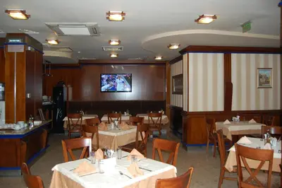 a dining room with tables and chairs and a tv at Nadejda Hotel in Sofia